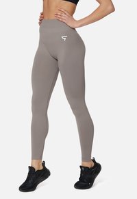 Leggings grigi alti in vita realizzati in tessuto elasticizzato, con una silhouette slanciata e un piccolo logo bianco sull'anca.