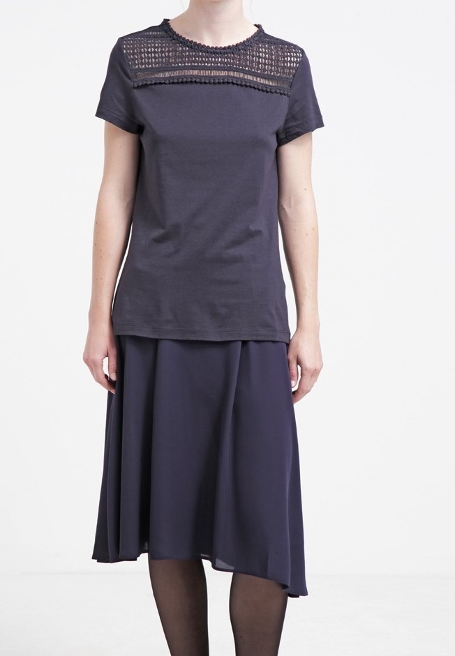Tmavě šedé tričko s texturovanou krajkovou vsadkou na výstřihu, spárované s volnou tmavou sukní. Jednoduchý, měkký materiál, délka po kolena.