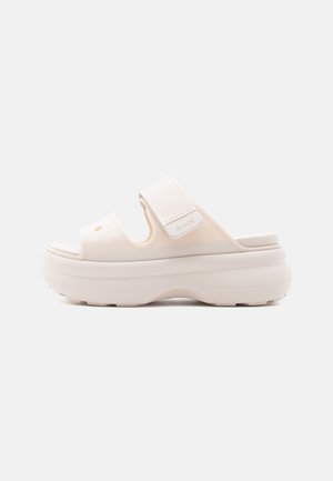 Beige platformsandal med tyk sål, åben tå og justerbar velcrolukning over toppen.