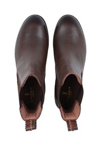 Brązowe skórzane botki za kostkę o gładkiej fakturze. Posiadają elastyczne boki oraz pętelkę do wsuwania z tyłu. Widoczne oznakowanie wewnętrzne.