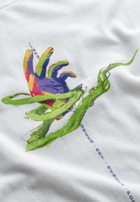 Witte stof met een kleurraf grafiek van een hand in paars, rood en groen, verweven met groene bladeren. Tekst is opgenomen in het ontwerp.