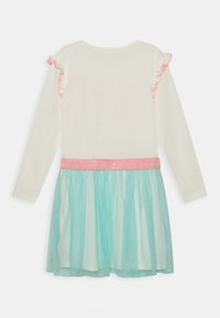 Šaty s dlouhým rukávem, které mají bílý vršek, růžové volánkové akcenty na rukávech a tyrkysovou tylovou sukni s růžovým třpytivým páskem.