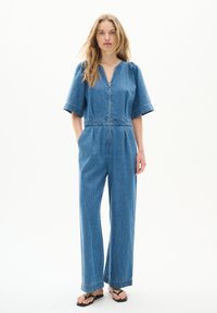 Jeans-Overall mit kurzen Puffärmeln, Reißverschluss und Seitentaschen. Hellblauer Stoff mit Kontrastnähten und weitem, lässigem Bein.