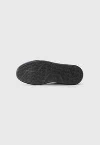 Sola de sapato de borracha preta com um padrão de aderência texturizado, apresentando um sulco central e bordas curvadas para flexibilidade.