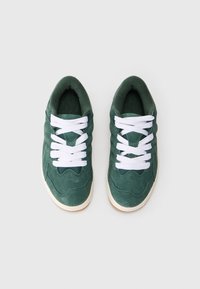 Tenisi verzi din suede cu șireți albi, având un superior texturat și o talpă contrastantă de culoare deschisă. Design cu vârf rotund și guler căptușit.