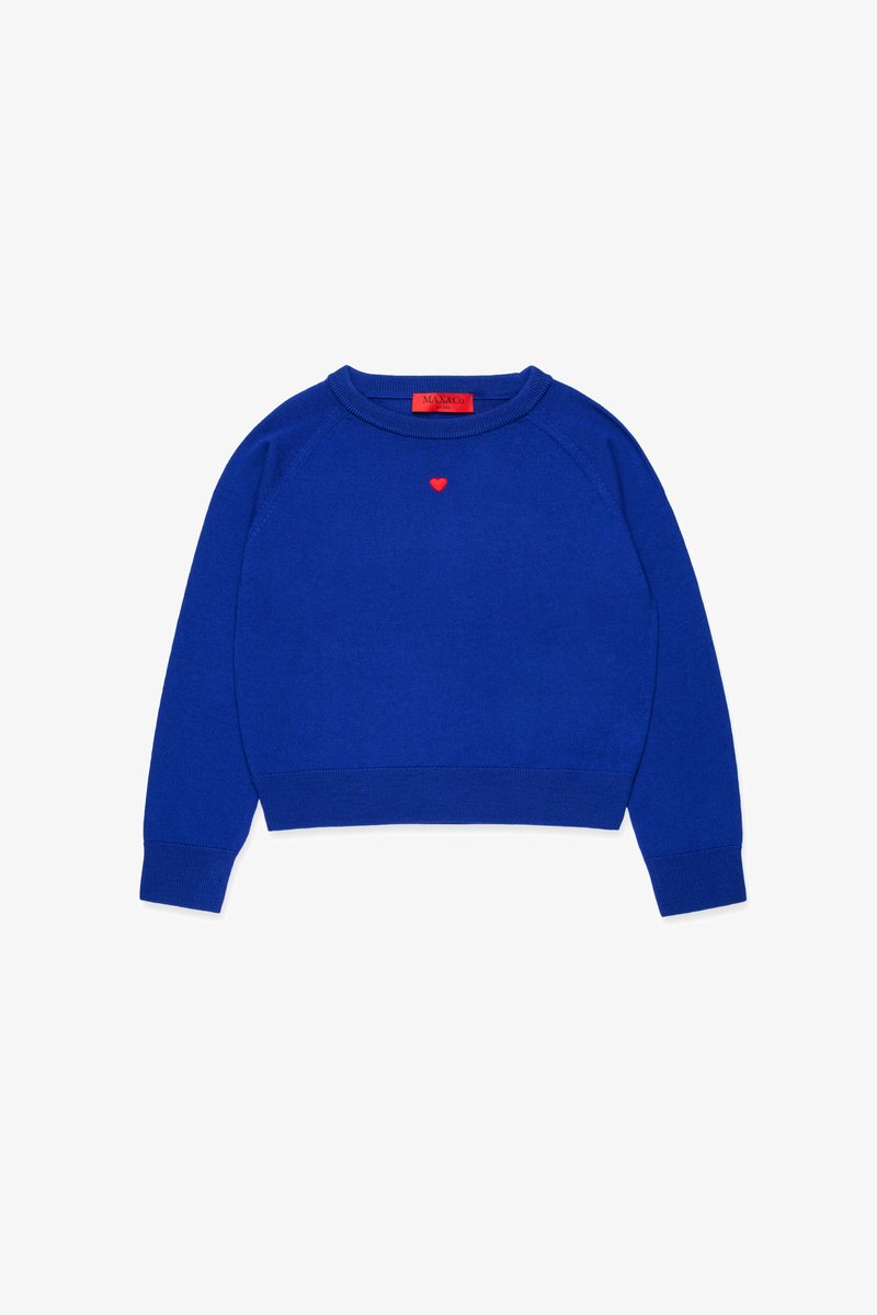 Blauer Strickpullover mit Rundhalsausschnitt und Raglanärmeln, versehen mit einem kleinen roten Herzen, das auf der Brust gestickt ist. Das Etikett ist rot.