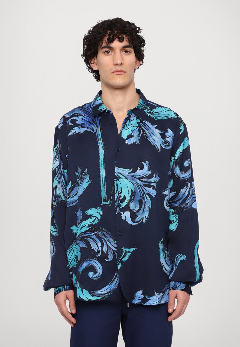 Marineblauwe langearmshirt met een blauw abstract bloemenpatroon, gemaakt van zacht materiaal, met een knoopsluiting aan de voorkant en een relaxte pasvorm.