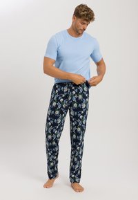 Lichtblauw T-shirt met korte mouwen, gecombineerd met marineblauwe pyjamabroek met bloemenpatroon, voorzien van groene en blauwe accenten en een elastische tailleband.