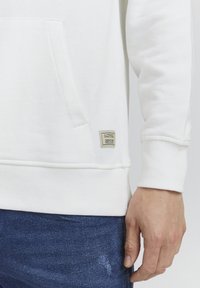 Witte katoen sweatshirt met ribbelmanchetten en -zoom, voorzien van een voorzak. Een klein label is nabij de onderzoom gestikt.