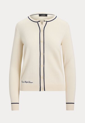 Κρεμ ζακέτα από απαλό πλεκτό ύφασμα με στρογγυλή λαιμόκοψη, ναυτικό τελείωμα και πέντε κουμπιά. Κεντημένο λογότυπο στο κάτω αριστερό μέρος.