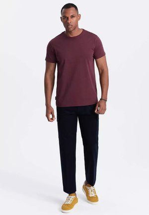 Camiseta corta de manga marón, pantalones negros y zapatillas amarillas. El conjunto presenta un corte relajado con una textura suave y detalles de diseño mínimos.