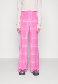 Pantalons à jambes larges à carreaux roses avec taille haute, présentant des lignes blanches dans un motif de damier. Tissu doux avec une texture lisse.