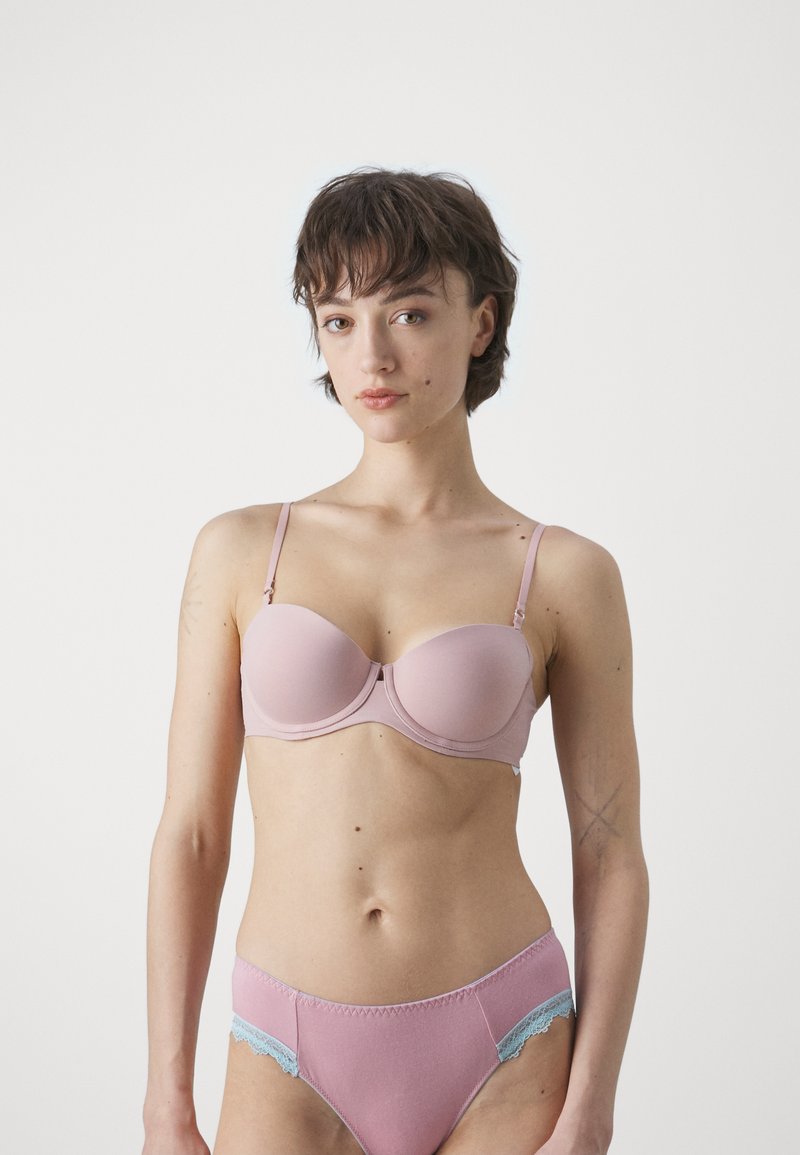 Reggiseno imbottito rosa chiaro con bretelle regolabili e ferretto; le mutandine a vita alta abbinate presentano dettagli in pizzo blu lungo i bordi.