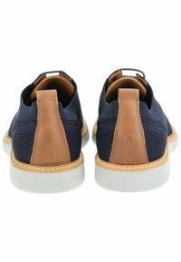 Scarpe in mesh marine con dettagli in pelle marrone, dotate di un tacco alto e suola in gomma bianca. Progettate per comfort e traspirabilità.