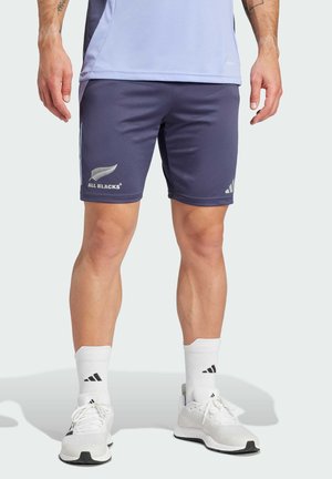 Marine atletikshorts med "ALL BLACKS" logo, lavet af glat stof, med elastisk talje og sidelommer; båret med hvide sokker og sko.