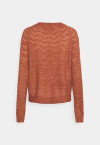Pull tricot couleur rouille à manches longues, avec un motif en zigzag texturé et un col rond. Coupe courte et ajustement ample.