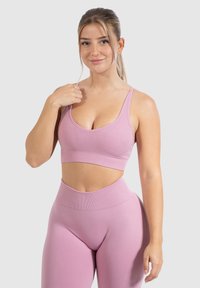 Top corto atlético rosa y leggings de cintura alta, material suave, textura acanalada, tirantes anchos, corte prominente a la altura de la cintura, diseño sin costuras.