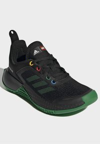 Černé tenisky Adidas s zelenou podrážkou, třemi zelenými pruhy, vícolorovými očky, logy Adidas a LEGO na jazyku a texturovaným detailem podrážky.