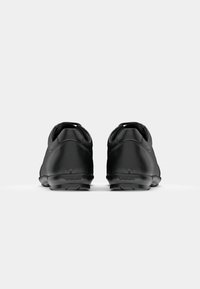 Chaussures en cuir noir avec une texture lisse, une forme arrondie et un profil bas, présentant un logo au talon et des détails de couture subtils.