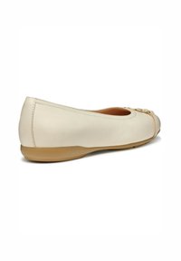 Bailarina beige con upper de cuero liso, puntera redondeada, acentos transparentes y suela de goma flexible.