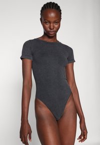 Mørkegrå ribbestrikket body med korte ermer, høyt kutt på bena og en tettsittende design. Glatt tekstur og minimalistisk stil, ingen synlige detaljer.