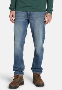 Verblasste blaue Jeans im geraden Schnitt, mit einem klassischen Fünf-Taschen-Design und dezenten Nähdetails entlang der Nähte.