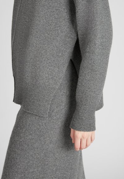 Grauer Strickcardigan mit lockerer Passform, gerippten Bündchen und weichem Material; verfügt über einen leichten Schulterabfall und seitliche Schlitzdetails.