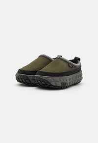 Olíva zöld velúr slip-on cipők fekete gumitalppal. Szürke varrással és texturált, párnázott talppal rendelkezik a tapadás érdekében.