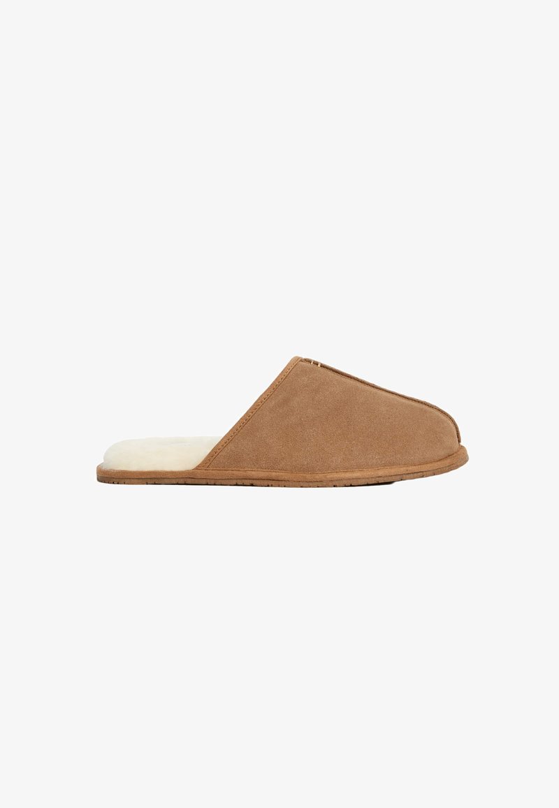 Pantofole in suede marrone con una morbida fodera in pelliccia beige, design a punta chiusa, suola piatta e dettagli di cucitura minimi lungo i bordi.