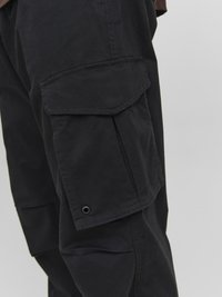 Black cargo pants with side pockets, made of durable fabric. Features reinforced seams and a matte finish. Designed for functionality.