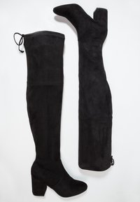 Botas negras hasta el muslo hechas de suave ante con un tacón cuadrado y un cordón en la parte superior para un ajuste ajustable, con costuras sin juntas.