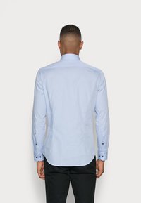 Lichtblauw overhemd met lange mouwen, met een slim fit, spread collar, en zwarte knoopaccenten op de manchetten, met een gladde, geweven textuur.
