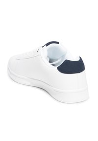 Sneaker bianco con finitura in pelle liscia, caratterizzato da un tallone in suede blu navigante e suola in gomma bianca, che mostra un classico design low-top.