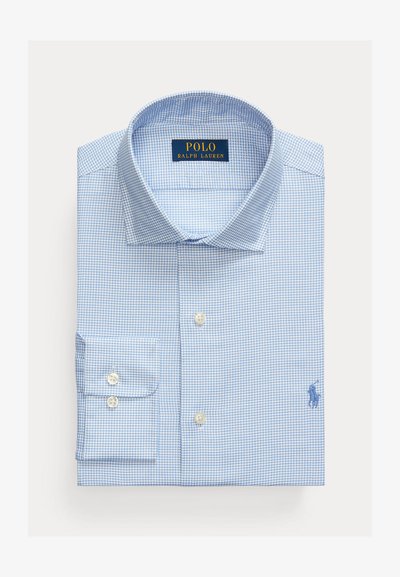 Gaiši zils raibs krekliņš, kas izgatavots no auduma ar patīkamu tekstūru. Aprīkots ar pogām pie apkakles un nelielu izšūtu logotipu uz krūšu.