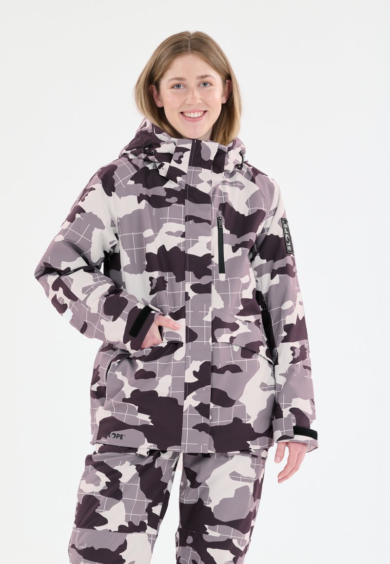 Kamoflaažisukset, tummades tona sinisistä, purpurasta ja valkoisesta, joissa on huppu, vetoketjullinen tasku ja tarranauhat. Tasainen, vedenpitävä materiaali.