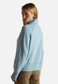 Pulover cu guler înalt, de culoare albastru deschis, din tricot moale, cu textură striată și mâneci lungi. Prezintă o croială lejeră și un tiv striat în contrast.