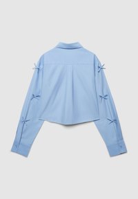 Camicia corta azzurro chiaro con colletto e maniche lunghe, caratterizzata da numerosi dettagli a fiocco sulle maniche e un design con pieghe sul retro.