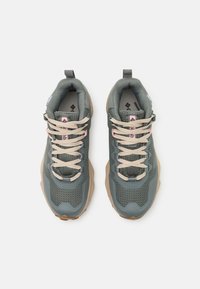 Sneakers z zieloną siateczką na cholewce, beżowymi sznurowadłami i grubą gumową podeszwą. Zawierają detale logo oraz wyściełany kołnierz dla wygody.