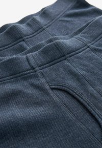 Mörkblå bomullssweatpants med texturerat tyg, elastisk midja och subtil sömdetaljering. Fickor synliga på båda sidor.