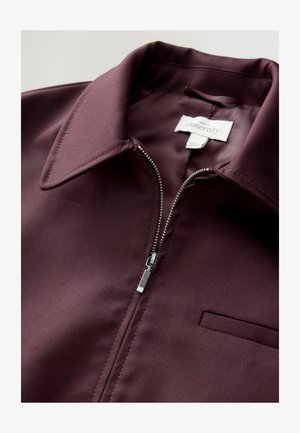 Burgundy maternity jacket with a smooth texture, zippered front, pointed collar, and a chest pocket. Fabric appears lightweight and durable.