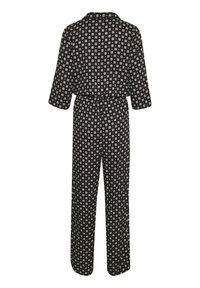 Combinaison noire à manches longues avec motif floral circulaire blanc, jambes larges, col avec revers et taille élastique, vue de dos.