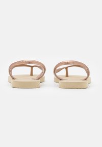 Sandali di gomma rosa con una superficie liscia, design con punta aperta e suole in tan texturizzato. Presentano due cinture curve sul retro.
