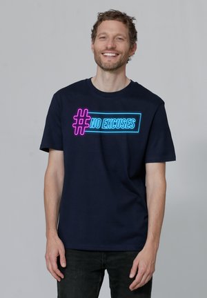 Marineblaue Baumwoll-T-Shirt mit dem Aufdruck "#NO EXCUSES" in leuchtend pink und blauer Neon-Schrift über der Brust. Kurze Ärmel und Rundhalsausschnitt.
