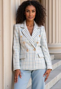 Jasnoniebieska marynarka w kratę o podwójnym zapięciu, z złotymi guzikami i bocznymi kieszeniami, w zestawie z dopasowanymi jasnoniebieskimi spodniami.