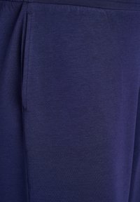 Close-up of dark blue fabric pant leg showing side seam and subtle texture with a vertical pocket opening.