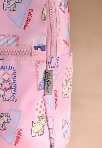 Rózsaszín szövet hátizsák játékos kutya mintákkal, cipzáras záródással, szövetcímkével és különböző színű geometrikus díszítésekkel.