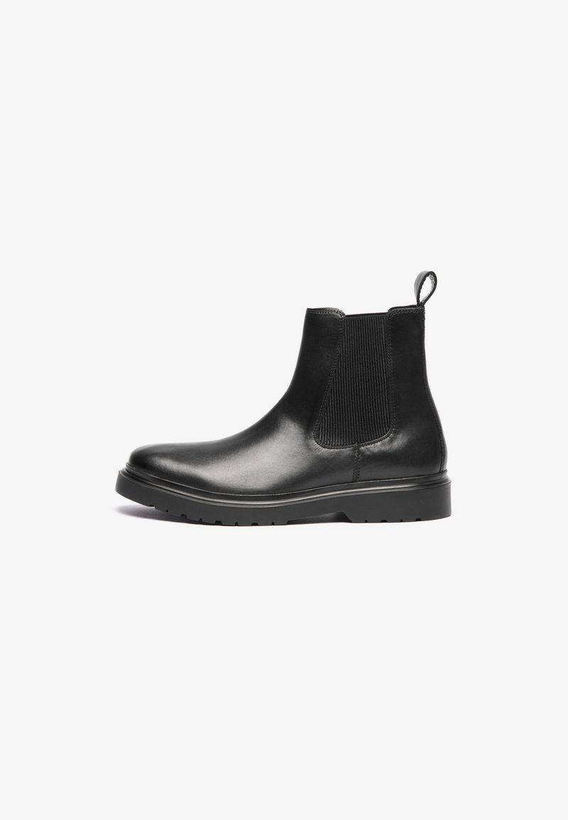 Svarta läder chelsea boots med elastiska sidopaneler, rund tå, dragflik vid hälen och texturerad gummisula för grepp.