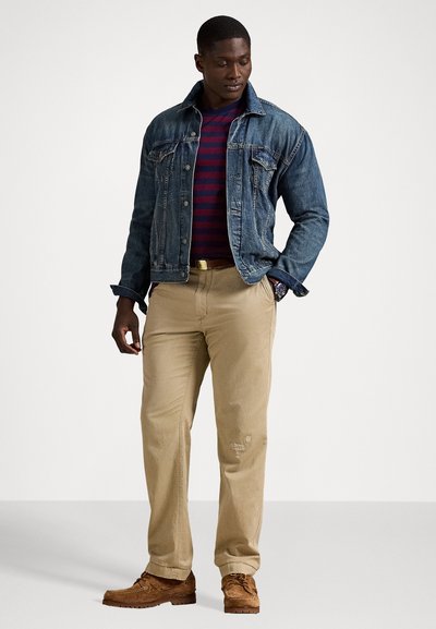 Τζάκετ από τζιν, μπλουζάκι με ρίγες σε ναυτικό μπλε και κόκκινο, καφέ παντελόνι, καφέ σουέτ υποδήματα. Διαθέτει μπροστινές τσέπες, ζώνη και υφή υφάσματος.