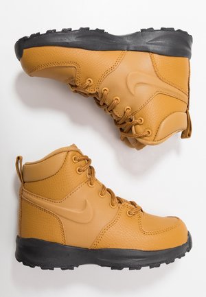 Dos botas de senderismo altas de color marrón claro con suelas negras, cordones y un sutil logo swoosh en el lateral, mostradas desde vistas lateral e inferior.