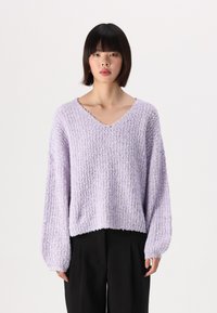 Sweater de linho lavanda claro com um padrão de malha texturada, corte solto e mangas bufantes; combinado com calças largas pretas.